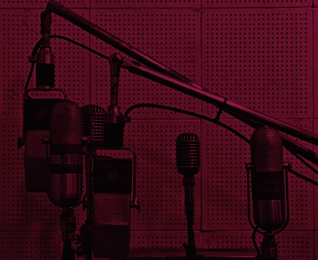 A cluster of vintage studio microphones on a pegboard wall